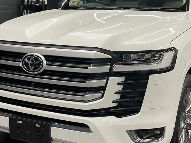 A white Toyota LandCruiser, washed, under the lights of a car care bay.